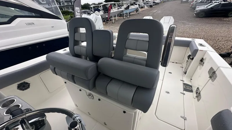 Slide: The Image of 2025 Boston Whaler 330 Outrage boat interior with gray seating and steering wheel. - 17