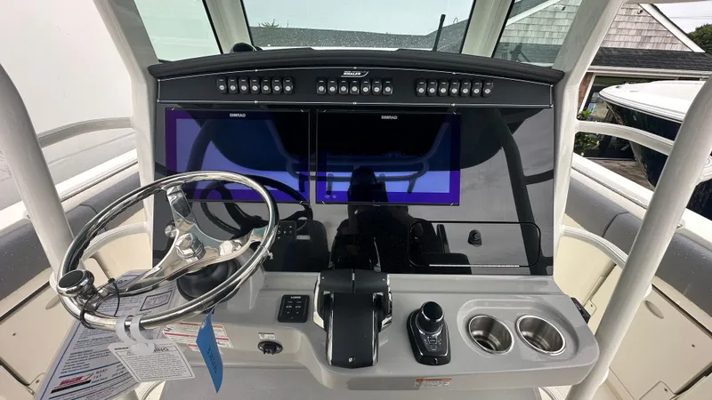 Slide: The Image of 2025 Boston Whaler 330 Outrage helm with dual Simrad displays and stainless steel steering wheel. - 25
