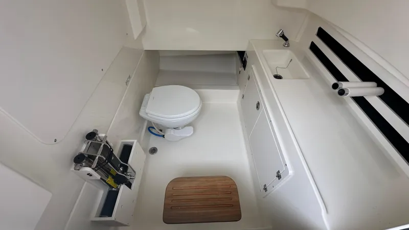 Slide: The Image of 2025 Boston Whaler 330 Outrage cabin with toilet, sink, and storage compartments. - 28