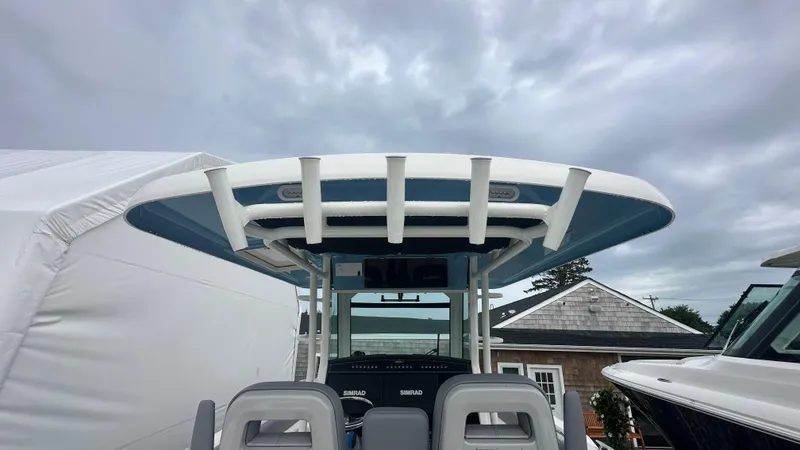 Slide: The Image of 2025 Boston Whaler 330 Outrage boat with T-top and Simrad electronics under cloudy sky. - 31