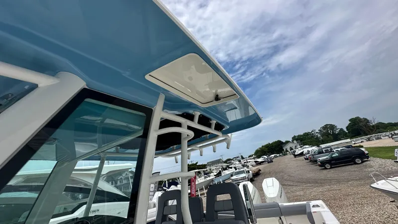 Slide: The Image of 2025 Boston Whaler 330 Outrage boat with blue canopy, parked in a marina. - 34