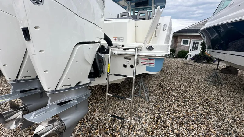 Slide: The Image of 2025 Boston Whaler 330 Outrage boat with dual engines and ladder on gravel surface. - 4
