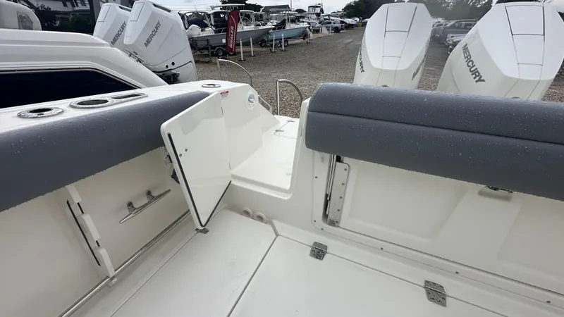 Slide: The Image of 2025 Boston Whaler 330 Outrage boat interior with Mercury engines, featuring seating and storage. - 5