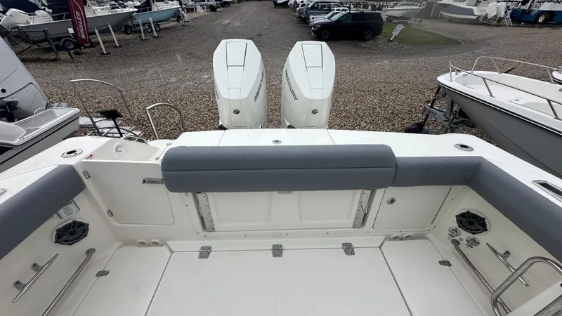 Slide: The Image of 2025 Boston Whaler 330 Outrage boat interior with dual engines in a marina setting. - 7