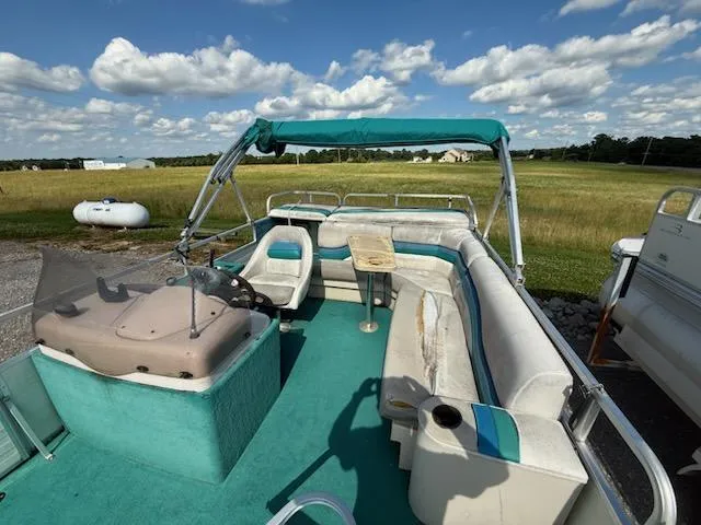 Slide: The Image of 1998 Lowe Family 245 pontoon boat with teal interior and canopy, parked in a grassy area. - 7