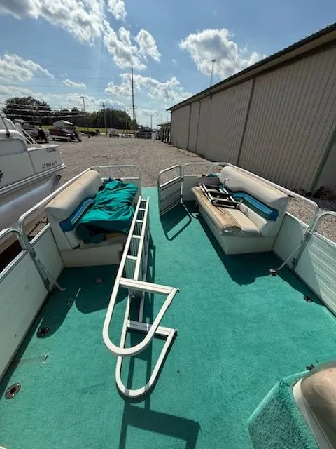 Slide: The Image of 1998 Lowe Family 245 pontoon boat with teal carpet and seating, docked outdoors. - 9