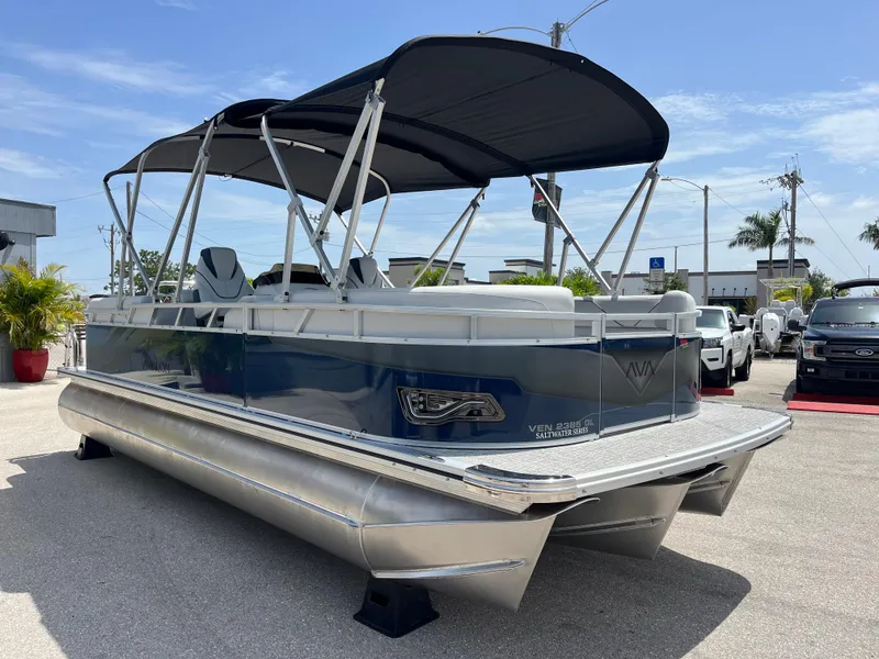 Slide: The Image of 2025 Avalon 2385 Venture Quad Lounger Tri Toon boat with canopy, parked outdoors. - 3