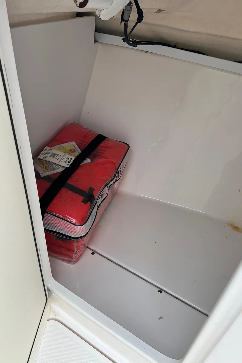 Slide: The Image of Storage compartment in 2013 Everglades 230 Dual Console boat with red life jacket pack. - 24