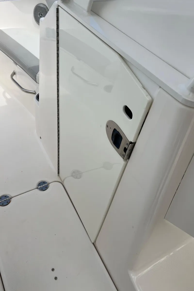 Slide: The Image of 2013 Everglades 230 Dual Console boat interior, featuring a white compartment door and sleek design. - 25