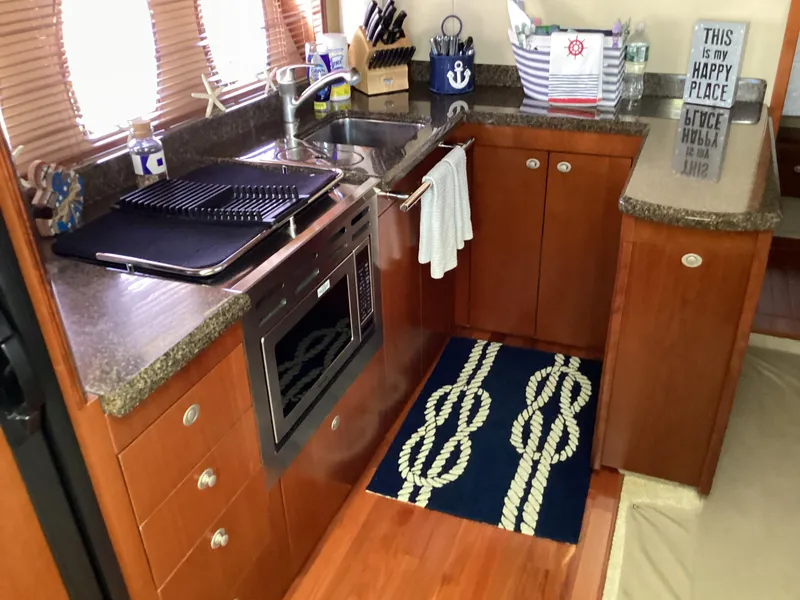 Slide: The Image of 2006 Sea Ray 48 Sundancer kitchen with wooden cabinets, granite countertops, and nautical decor. - 16