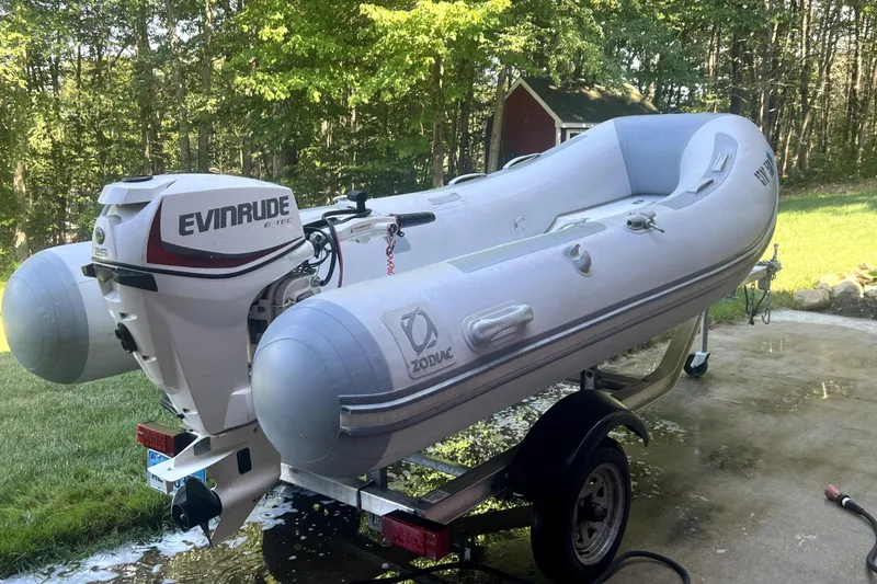 Slide: The Image of Inflatable Zodiac boat with Evinrude motor on trailer, outdoors in a wooded area. - 45