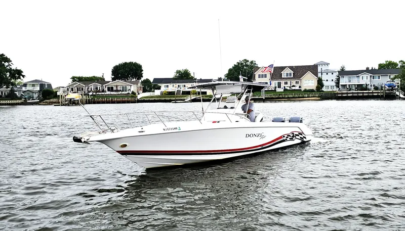 Slide: The Image of 1999 Donzi 35 ZF boat cruising on a calm river near waterfront homes. - 3