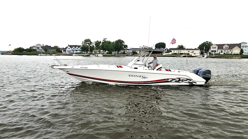 Slide: The Image of 1999 Donzi 35 ZF boat cruising on a calm river near waterfront homes. - 4