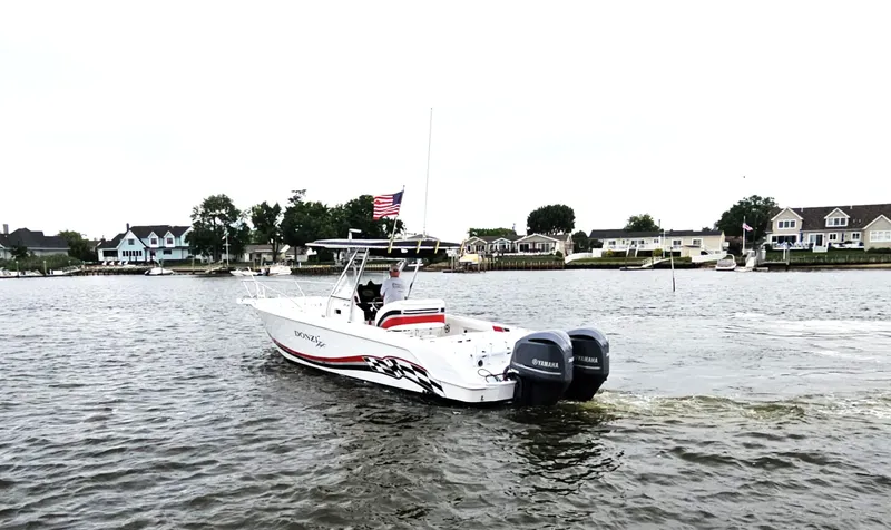 Slide: The Image of 1999 Donzi 35 ZF boat cruising on a scenic waterfront with houses in the background. - 5