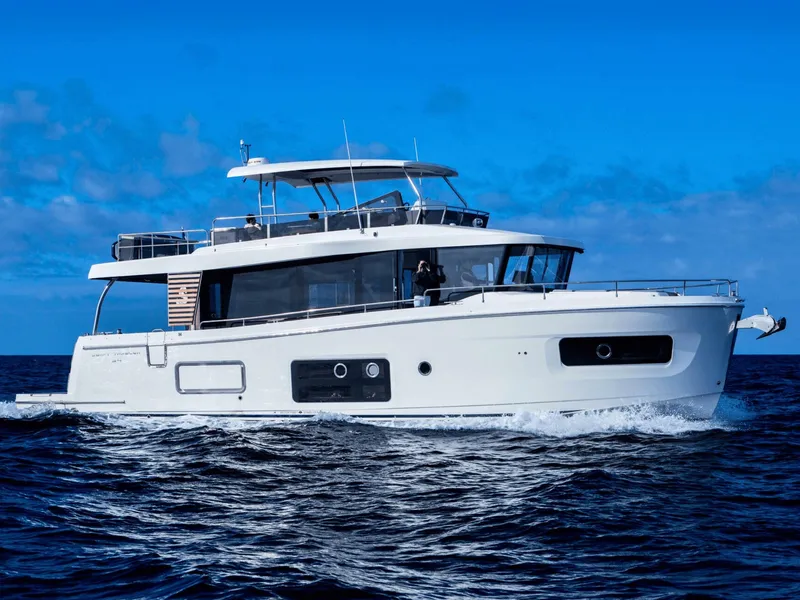 The Image of 2026 Beneteau Swift Trawler 54 cruising on open sea under clear blue sky. - 0