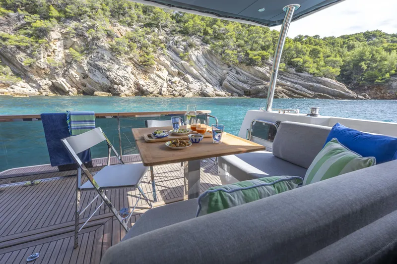 Slide: The Image of 2026 Beneteau Swift Trawler 54 deck with dining setup, scenic coastal view. - 17