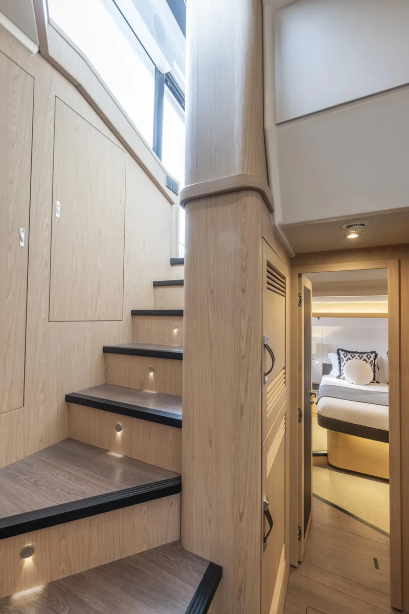Slide: The Image of Interior of 2026 Beneteau Swift Trawler 54, featuring wooden stairs and a cozy bedroom. - 20