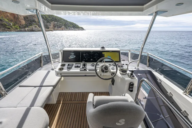 Slide: The Image of 2026 Beneteau Swift Trawler 54 helm with ocean view, featuring modern navigation equipment. - 23