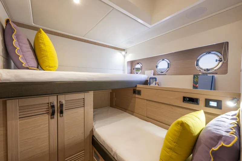 Slide: The Image of Interior cabin of 2026 Beneteau Swift Trawler 54 with bunk beds and portholes. - 29