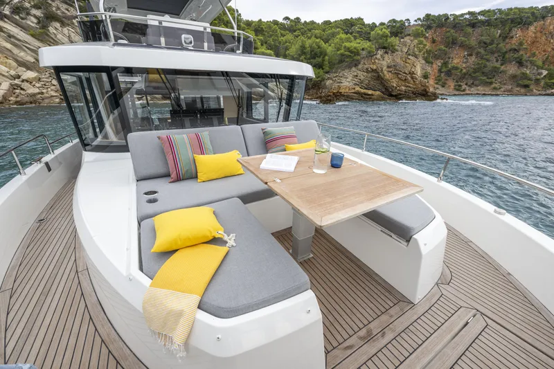Slide: The Image of 2026 Beneteau Swift Trawler 54 with outdoor seating, colorful cushions, and ocean view. - 6