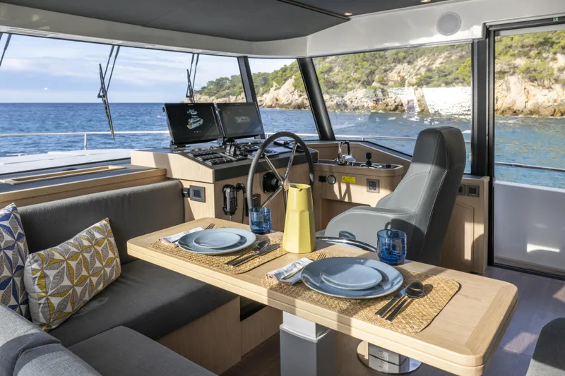 Slide: The Image of Interior of 2026 Beneteau Swift Trawler 54 with dining area and helm, overlooking the sea. - 7