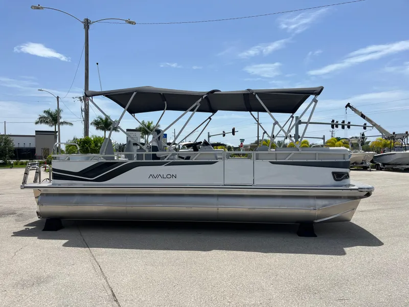 Slide: The Image of 2025 Avalon 2385 Venture 85 Tri Toon boat with canopy, parked outdoors. - 4