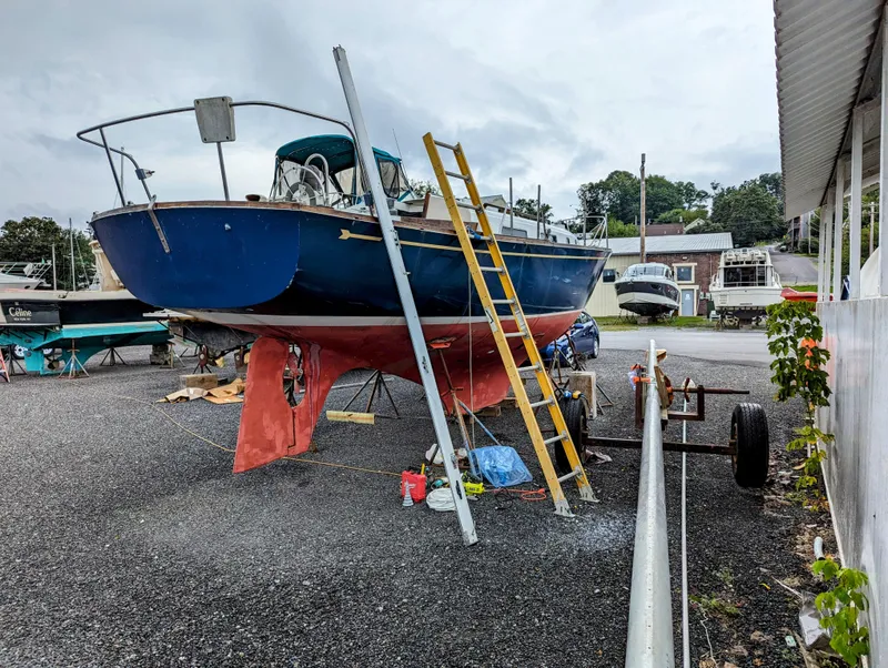 The Image of 1976 Bristol 34 sailboat on land, undergoing maintenance with ladder and tools nearby. - 0