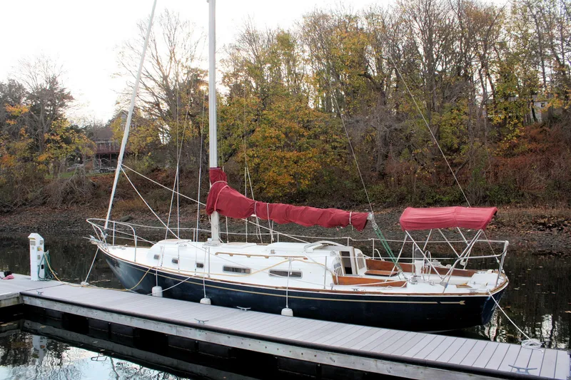Slide: The Image of 1976 Bristol 34 sailboat docked by autumn trees, featuring red sail covers. - 10