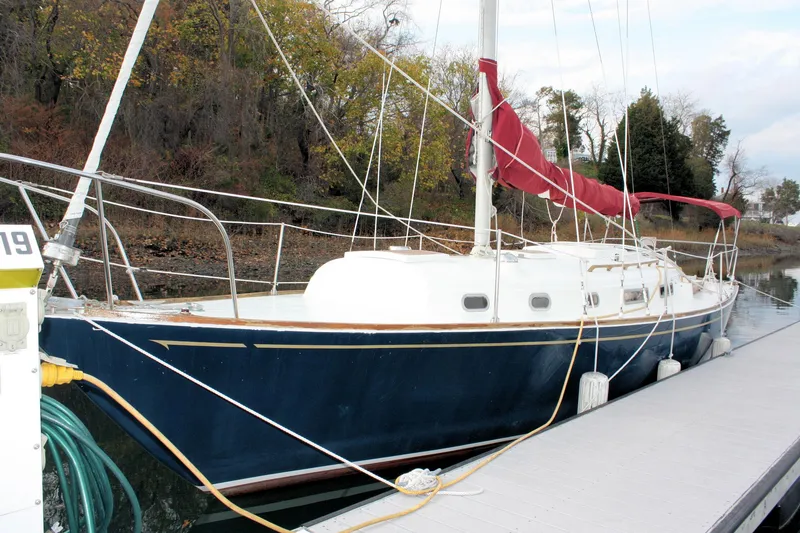 Slide: The Image of 1976 Bristol 34 sailboat docked, featuring a blue hull and red sail cover. - 20