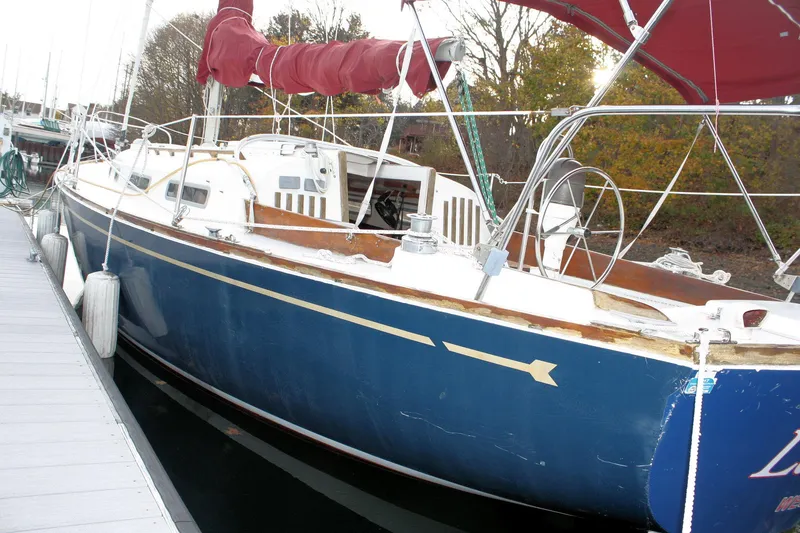 Slide: The Image of 1976 Bristol 34 sailboat docked, featuring a blue hull and red sail cover. - 21