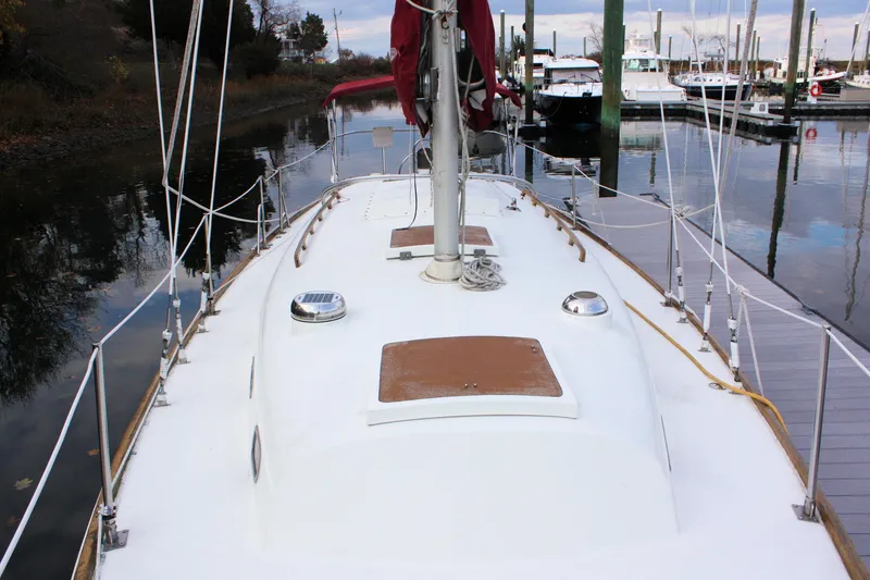 Slide: The Image of 1976 Bristol 34 sailboat docked, showcasing deck and mast in a serene marina setting. - 24