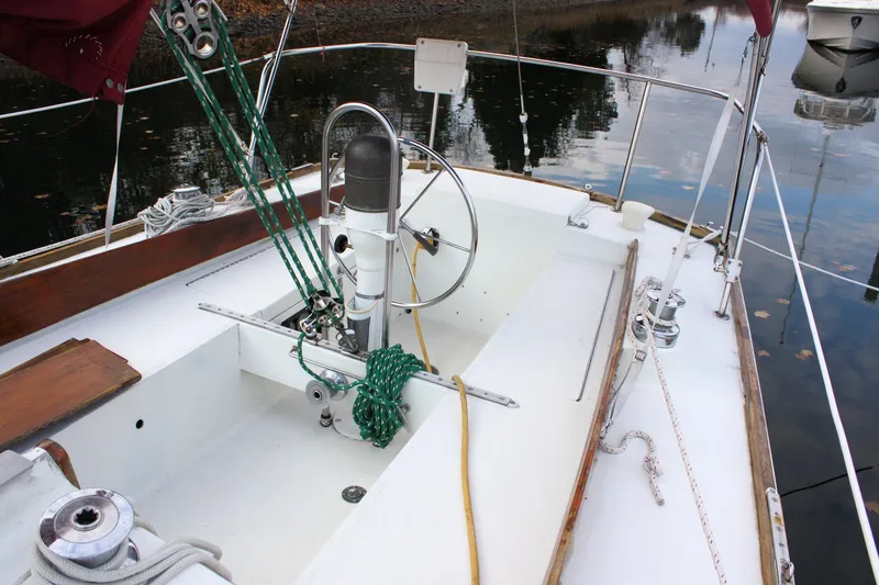 Slide: The Image of 1976 Bristol 34 sailboat cockpit with steering wheel and ropes, docked on calm water. - 26