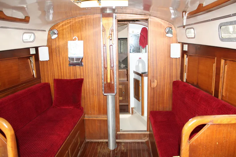 Slide: The Image of Interior of a 1976 Bristol 34 sailboat with red cushioned seating and wooden paneling. - 37