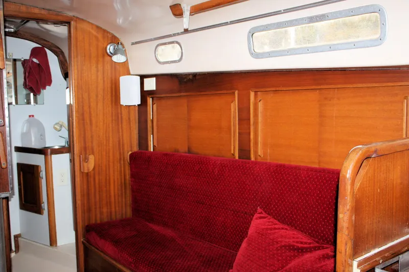 Slide: The Image of Interior of a 1976 Bristol 34 sailboat with red cushioned seating and wooden paneling. - 42