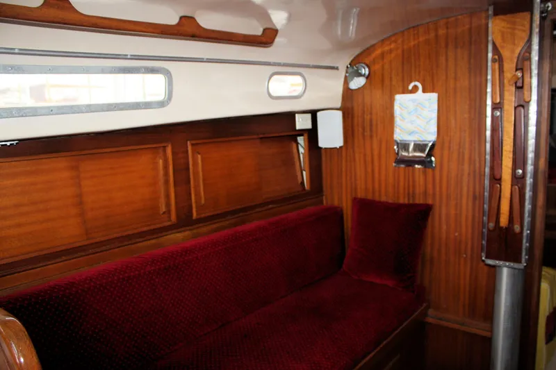 Slide: The Image of 1976 Bristol 34 yacht interior with red cushioned seating and wooden paneling. - 43