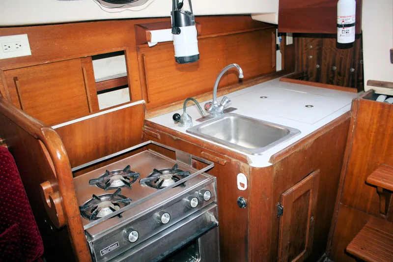 Slide: The Image of 1976 Bristol 34 yacht kitchen with stove, sink, and wooden cabinetry. - 44