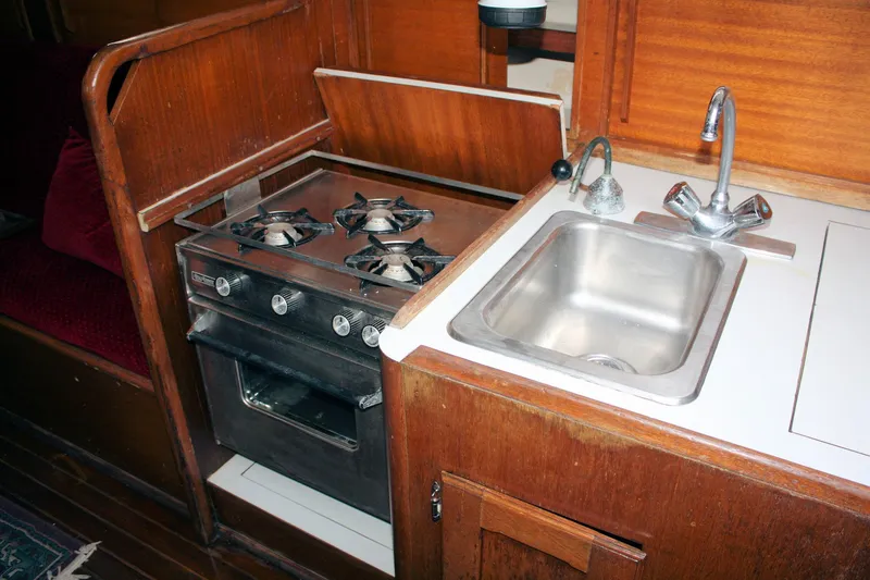 Slide: The Image of 1976 Bristol 34 yacht kitchen with stove and sink, featuring wooden cabinetry. - 46
