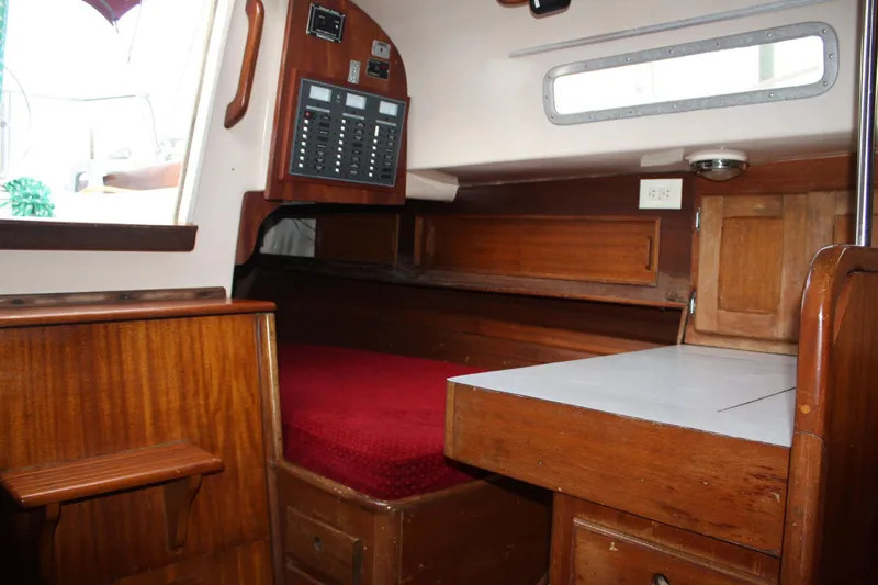 Slide: The Image of Interior of a 1976 Bristol 34 sailboat with wooden cabinetry and red bedding. - 49