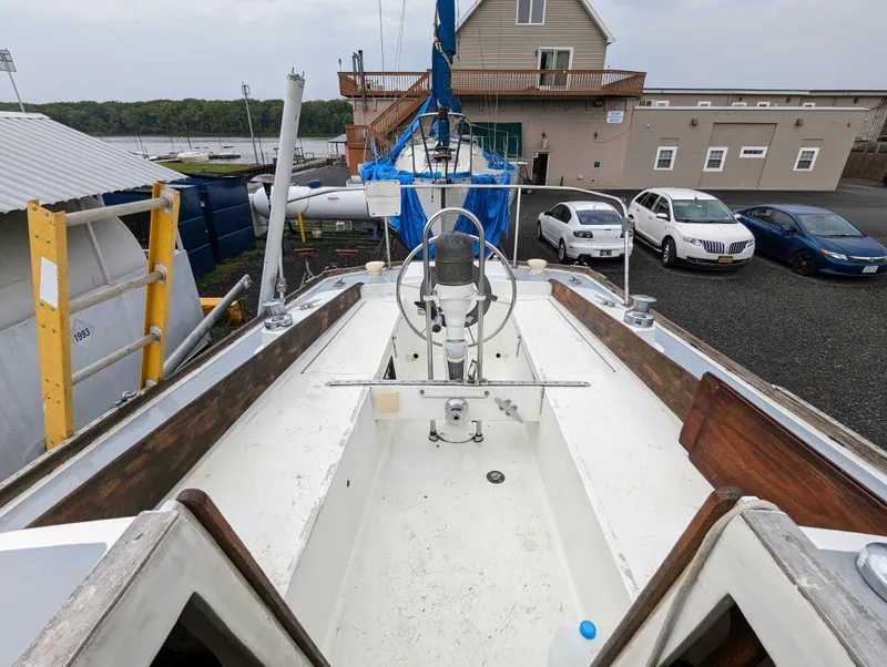 Slide: The Image of 1976 Bristol 34 sailboat cockpit view in a marina with parked cars and buildings. - 5