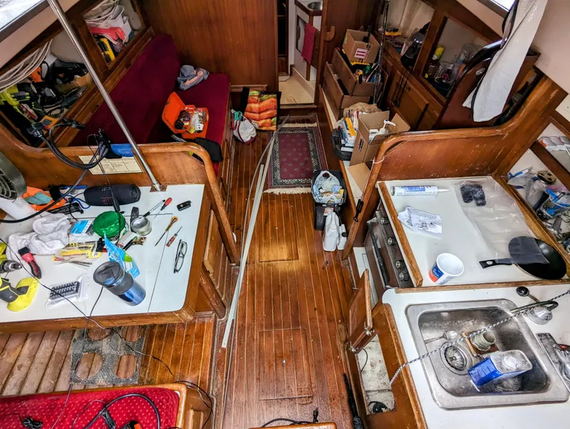 Slide: The Image of Interior of a 1976 Bristol 34 sailboat with wooden flooring and cluttered countertops. - 7