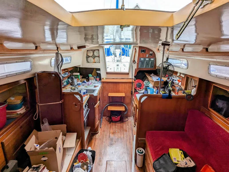 Slide: The Image of 1976 Bristol 34 sailboat interior with wooden finish, cluttered with various items and equipment. - 8