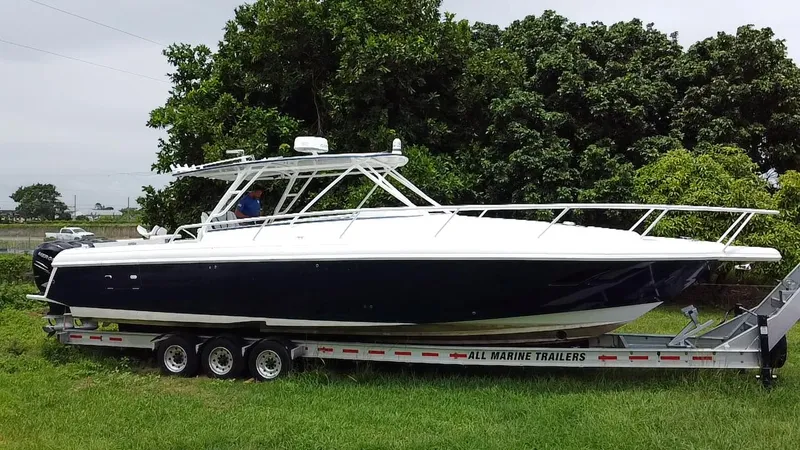 Slide: The Image of 2008 Intrepid 390 Sport Yacht on trailer, parked on grass, surrounded by trees. - 11