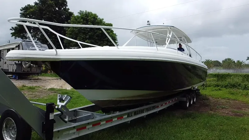 Slide: The Image of 2008 Intrepid 390 Sport Yacht on trailer, parked on grass, with trees in background. - 2