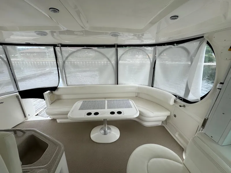 Slide: The Image of 2004 Sea Ray 390 Motoryacht interior with white seating and table, overlooking water. - 28