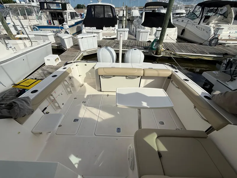 Slide: The Image of 2017 Pursuit DC 325 Dual Console boat interior with seating and storage, docked at marina. - 16