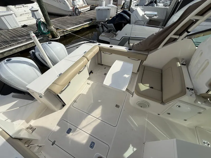Slide: The Image of 2017 Pursuit DC 325 Dual Console boat interior with seating and table, docked at marina. - 18