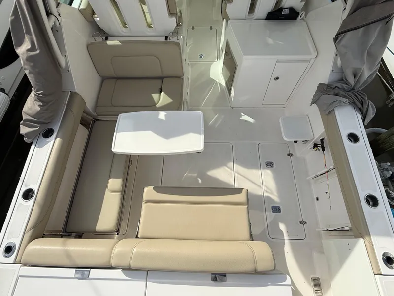 Slide: The Image of 2017 Pursuit DC 325 Dual Console boat interior with beige seating at marina. - 22