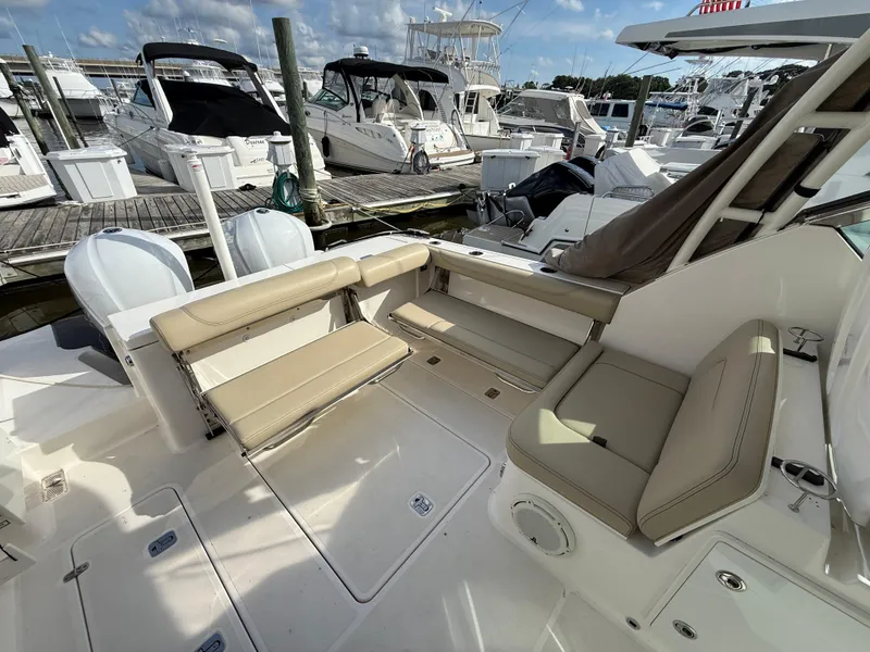 Slide: The Image of 2017 Pursuit DC 325 Dual Console boat interior with beige seating and white cabinetry. - 23
