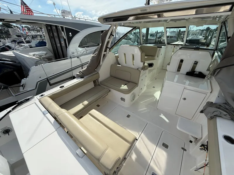 Slide: The Image of 2017 Pursuit DC 325 Dual Console boat interior at marina, featuring seating and storage. - 24