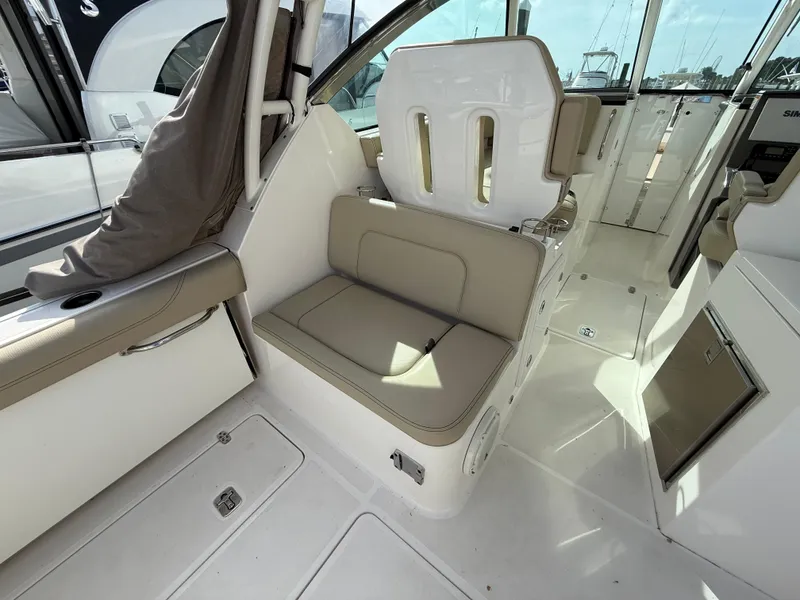 Slide: The Image of 2017 Pursuit DC 325 Dual Console interior with beige seating and marina view. - 29